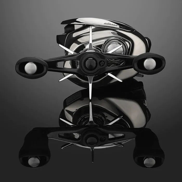 Eine Nahaufnahme der Gomexus Sternbremse 60 mm für Shimano in silberner und schwarzer Ausführung wird von vorne auf einer dunklen, reflektierenden Oberfläche gezeigt, wodurch die hochwertige Aluminiumkonstruktion hervorgehoben wird.