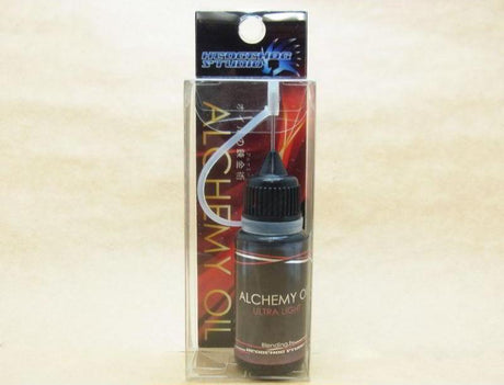 Das Hedgehog Studio Alchemy Oil Ultra Light Rollenöl wird in einer kleinen Plastikflasche mit spitzer Düse geliefert und ist in einer transparenten Box mit rot-schwarzer Grafik verpackt. Es eignet sich ideal für die Angelrollenpflege und trägt die Marke Hedgehog Studio auf der Oberseite.